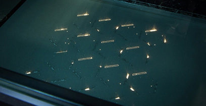 Metal powder is brushed away from a bed of intricate aluminum parts