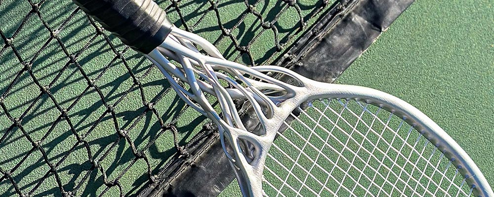 Tennis racket on a tennis court next to a net
