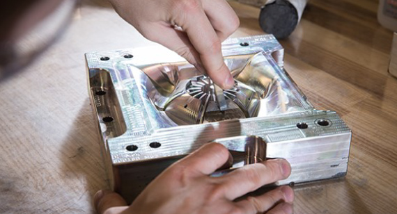 2 hands working on an auto part Bridge tooling