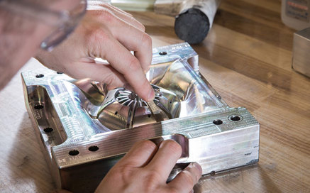 A person inspecting a high-precision aluminium mould in a workshop