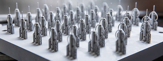 Rows of metal 3D-printed parts on a white surface